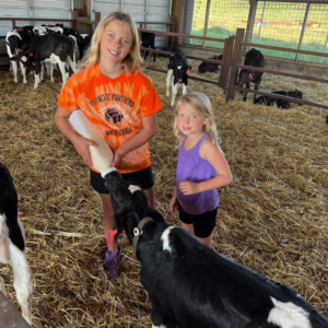 Prairie Raised Beef Summer Camp Farm Camp Sauk City, Wisconsin two girls feeding a calf a bottle